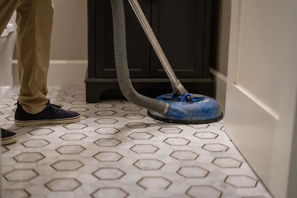 Ultra Brite technician deep-cleaning hexagon tile and grout with a rotary tool